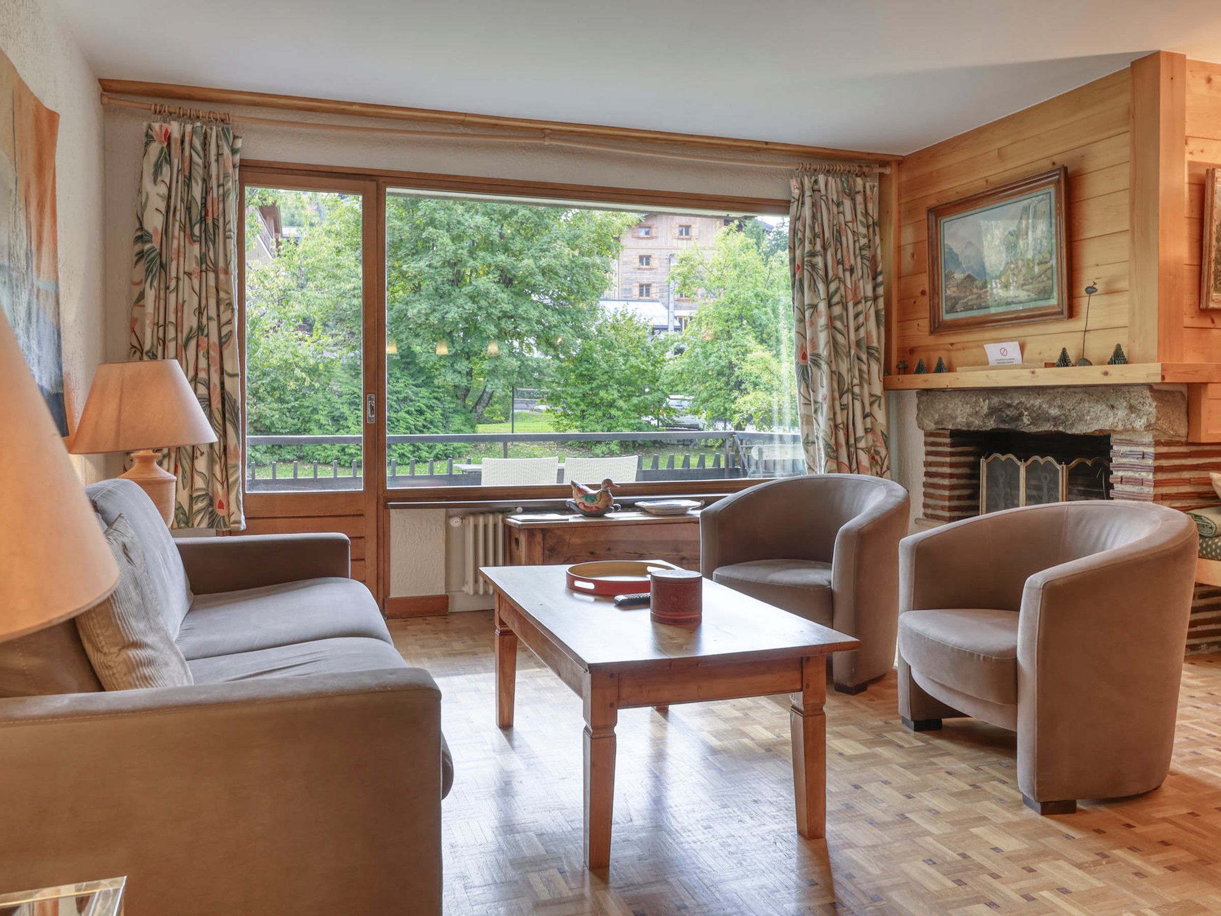 A cozy living room with a sofa, two armchairs, a wooden coffee table, and a fireplace.