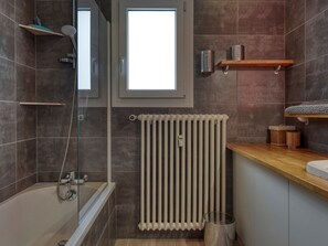 Een moderne badkamer met een badkuip, douche en een raam.