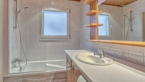 Une salle de bain moderne avec une baignoire, un lavabo et un grand miroir.