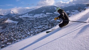 Un skieur sur une pente enneigée, avec une ville en arrière-plan.