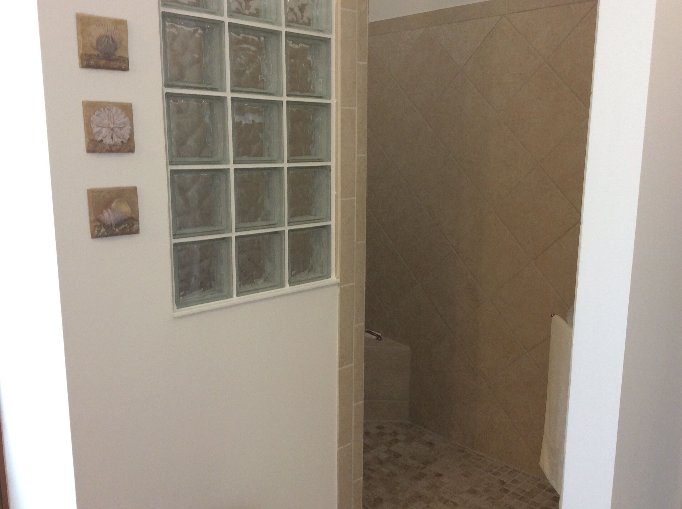 Une salle de bain avec une cabine de douche, un carrelage au sol et trois éléments décoratifs fixés au mur.