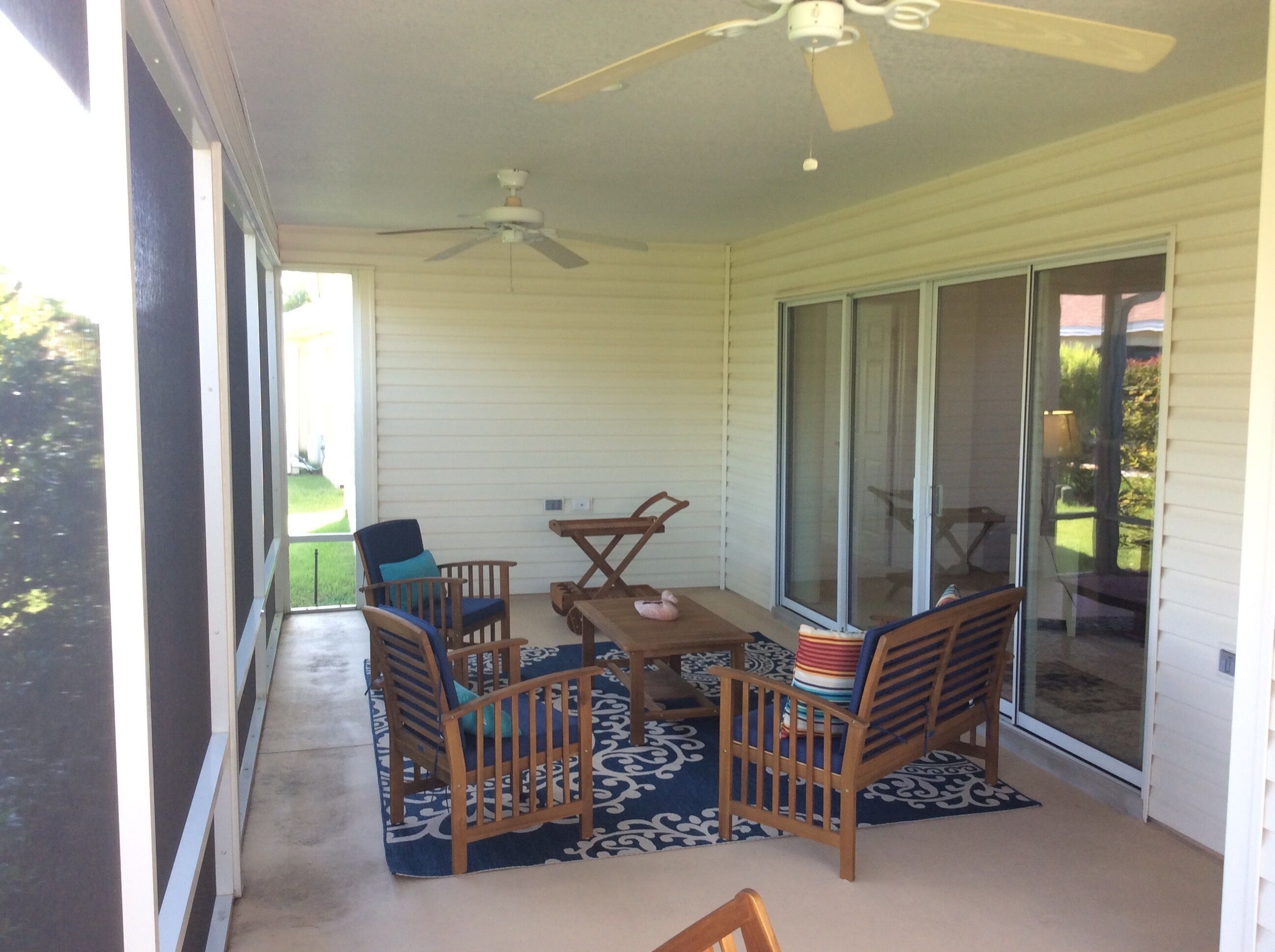 Un patio couvert avec un ventilateur de plafond, une table et quatre chaises.