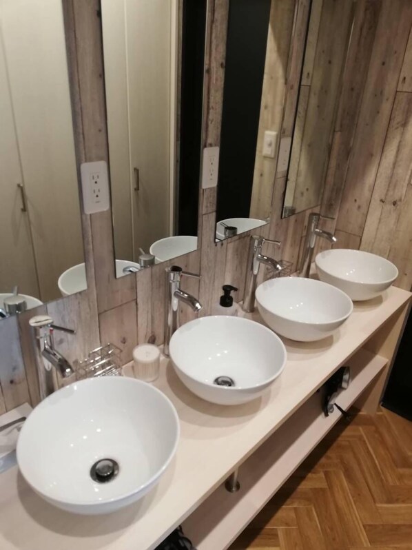 A bathroom with multiple sinks, wooden paneling, and a mirror.