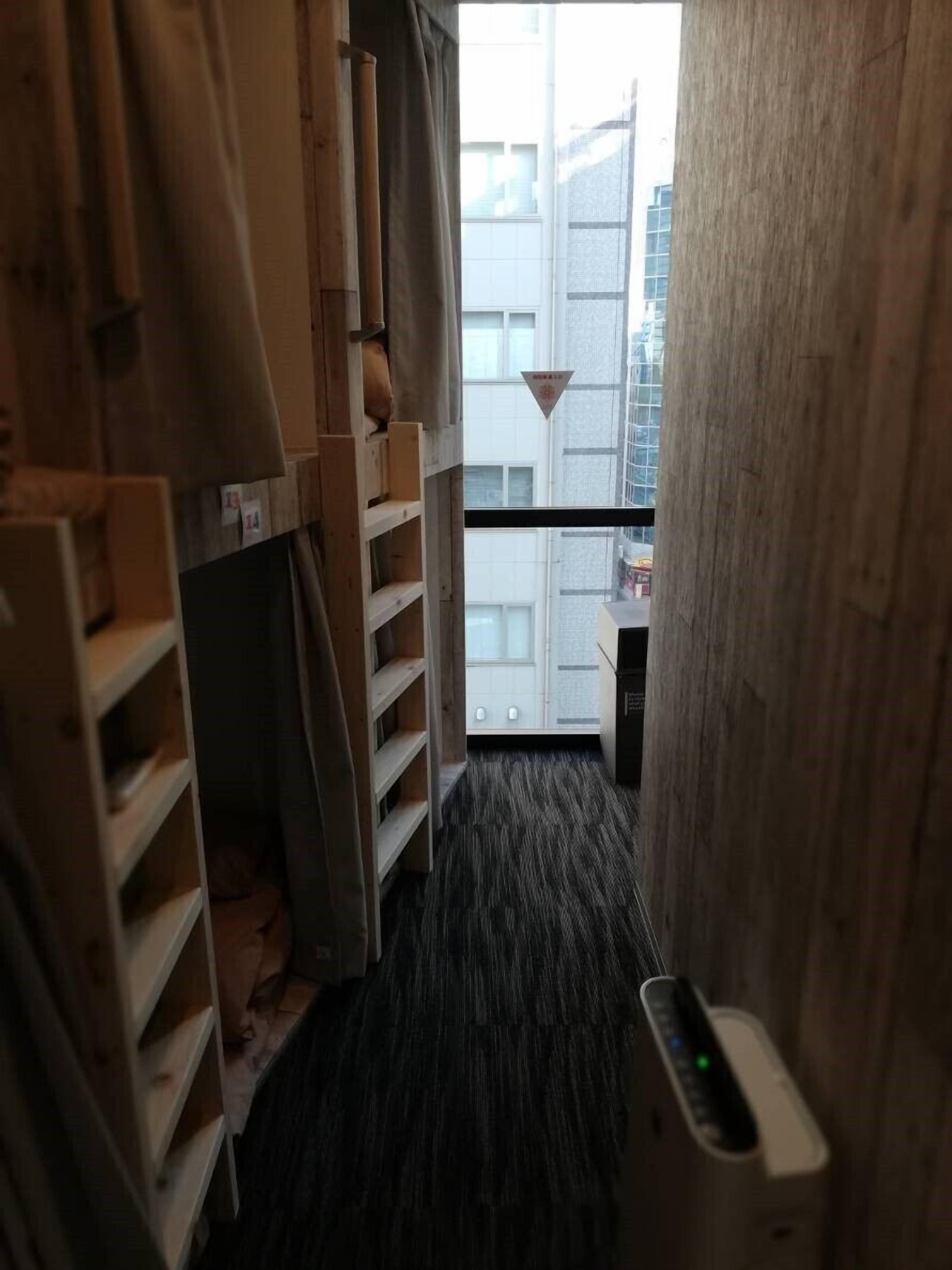A narrow corridor with wooden storage units on one side and a window at the end.