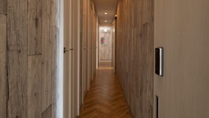 A hallway with wooden paneling on the walls and a herringbone patterned floor. - bnb+ Kanda - Hostel (Tokyo)