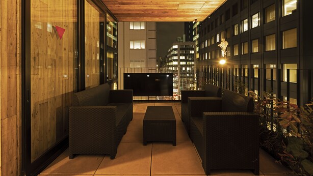 A rooftop lounge with wicker furniture, a flat-screen TV, and a wooden ceiling. - bnb+ Kanda - Hostel (Tokyo)