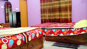 A bedroom with two beds, a wardrobe, a mirror, and a television.
