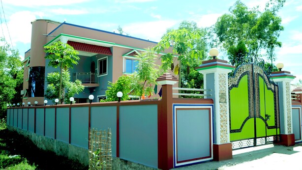 A residential house with a gated entrance, a balcony, and a well-maintained garden.