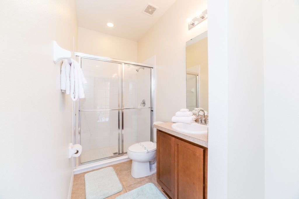 A modern bathroom with a glass-enclosed shower, a toilet, a sink with a mirror, and a towel rack.