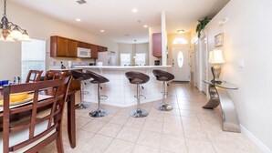 A modern kitchen with a central island, bar stools, and a dining area with a table and chairs.
