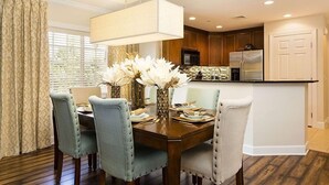 A dining area with a wooden table, four upholstered chairs, and a vase with white flowers. - Ov4262 - Reunion Resort - 3 Bed 3 Baths Condo (Kissimmee)