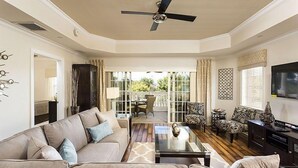 A spacious living room with a ceiling fan, a large window with curtains, a sofa set, and a television. - Ov4262 - Reunion Resort - 3 Bed 3 Baths Condo (Kissimmee)