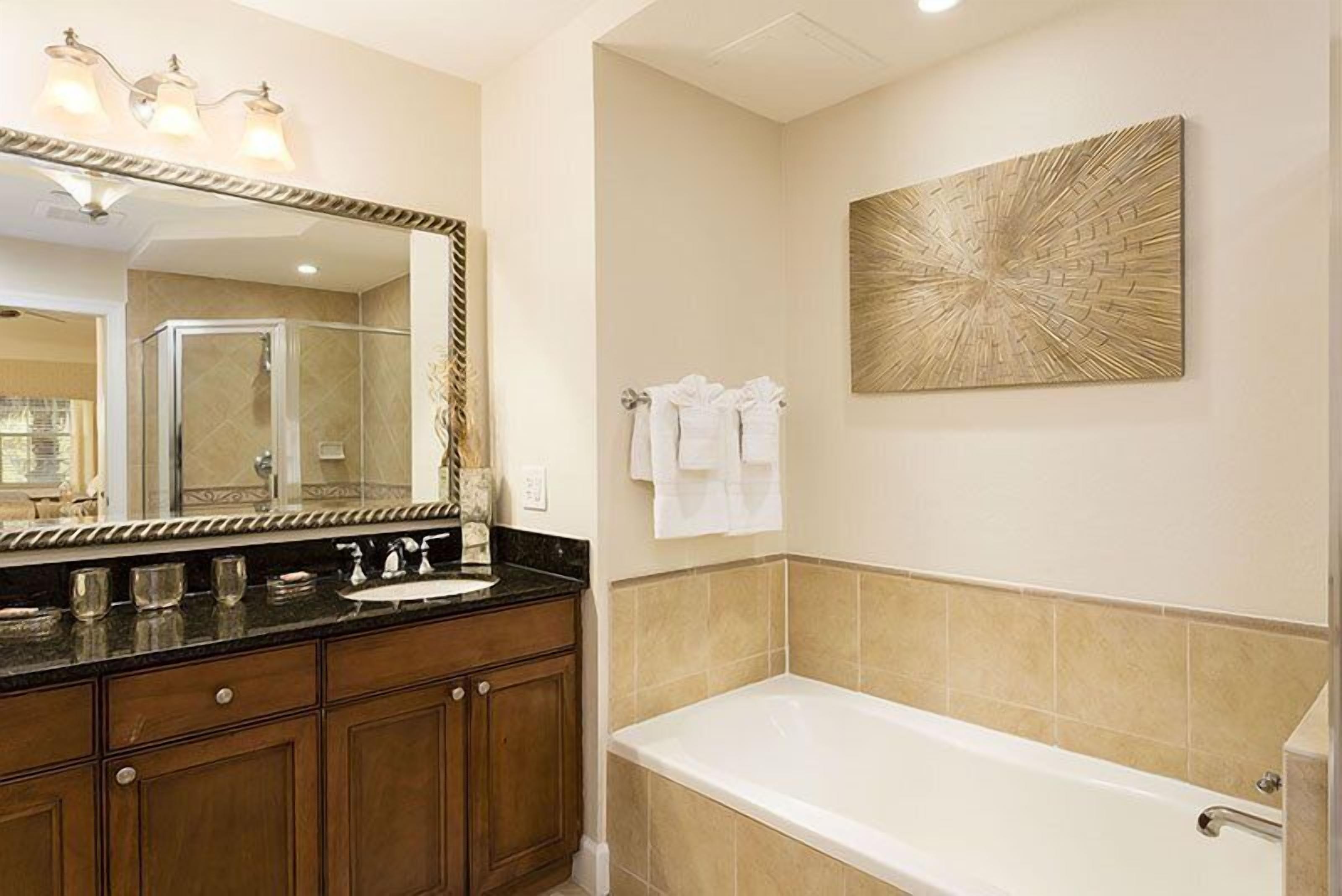 Une salle de bain avec un grand miroir, une baignoire et un porte-serviettes fixé au mur.