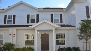 A two-story residential building with a front entrance, a small porch, and a mailbox.
