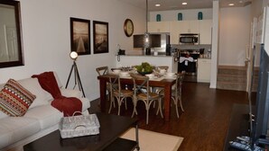 A modern living room with a sofa, coffee table, and dining area with chairs and a table set for a meal.