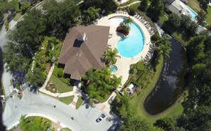 An aerial view of a residential property with a swimming pool, a covered patio, and a landscaped garden.