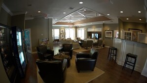 A spacious living room with a fireplace, comfortable seating, and a kitchen area visible in the background.