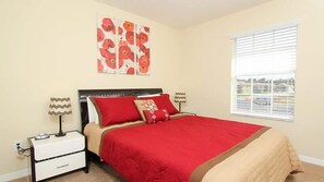 A bedroom with a bed, nightstands, a window, and artwork on the wall.