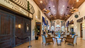 A lobby with wooden paneling, a cinema sign, and a seating area with patterned chairs and tables. - Ts226164 - Paradise Palms Resort - 4 Bed 3 Baths Signature Villa (Kissimmee)