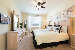 Cozy retreat with a large bed, nightstands, and a ceiling fan, featuring a TV, dresser, and artwork.