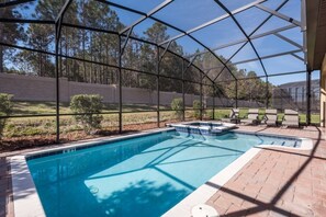 A covered outdoor swimming pool with a clear view of the surrounding landscape, including trees and a brick wall. - Ev239275 - Champions Gate Resort - 6 Bed 5 Baths Villa (Davenport)