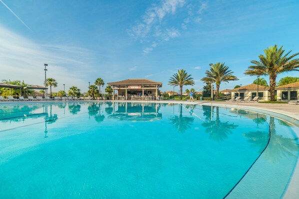 Relax by the pool surrounded by palm trees and lounge chairs under a shaded pavilion.