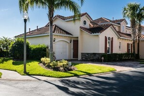 A two-story house with a beige facade, a red-tiled roof, and a front garage door. - Ss256681 - Tuscan Hills - 3 Bed 2 Baths Villa (Davenport)