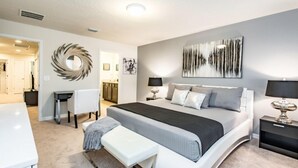 A modern bedroom with a large bed, bedside tables, a desk, and a chair. - Ev216592 - Windsor At Westside Resort - 5 Bed 4 Baths Townhome (Kissimmee)