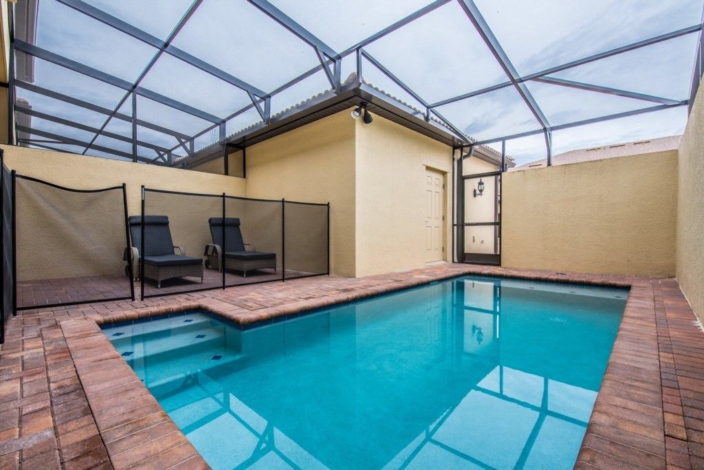 An indoor swimming pool with a glass ceiling, surrounded by lounge chairs and a brick floor.