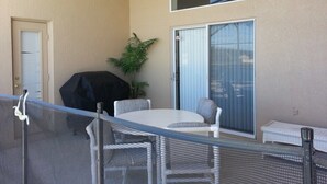 A balcony with a ceiling fan, a grill, a table with chairs, and a sliding glass door. - Br52637 - Indian Creek - 5 Bed 4 Baths Villa (Kissimmee)