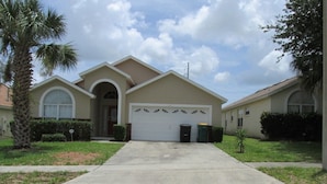 A single-story house with a garage, a front lawn, and a palm tree. - Br52637 - Indian Creek - 5 Bed 4 Baths Villa (Kissimmee)