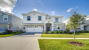 A two-story house with a garage, a front porch, and a well-maintained lawn.