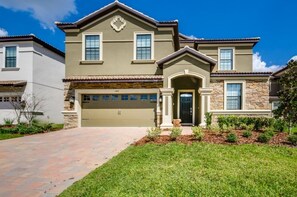 A two-story house with a garage, stone facade, and a well-maintained lawn. - Ev220208 - Champions Gate Resort - 8 Bed 5 Baths Villa (Davenport)