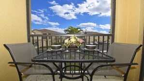 A balcony with a table set for two, featuring a vase with flowers and two wine glasses. - Fs55568 - Oakwater Resort - 2 Bed 2 Baths Townhome (Kissimmee)