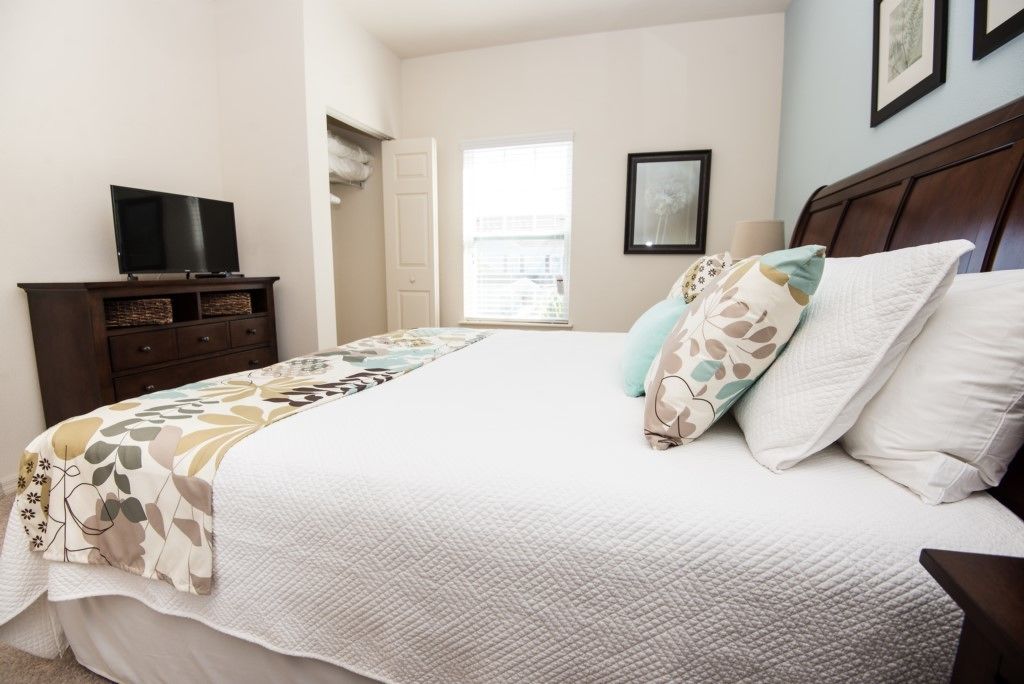A bedroom with a bed, a dresser, a television, and a window with a view.