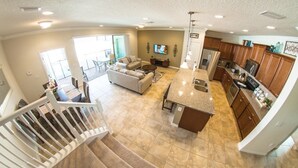 A spacious living area with a sofa, coffee table, and a kitchen with wooden cabinets and a granite countertop. - Fd88884 - Windsor At Westside Resort - 5 Bed 4.5 Baths Townhouse (Kissimmee)
