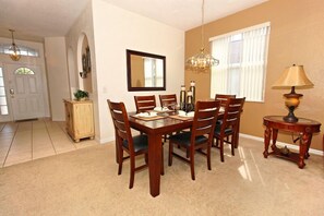 A dining room with a wooden table and chairs, a chandelier, and a lamp. - Ev54115 - Highlands Reserve - 5 Bed 3 Baths Villa (Davenport)