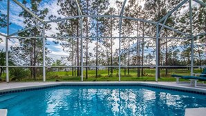 Une piscine offrant une vue dégagée sur les arbres environnants et dotée d’un espace abrité.