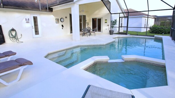 A swimming pool with lounge chairs and a covered patio area.