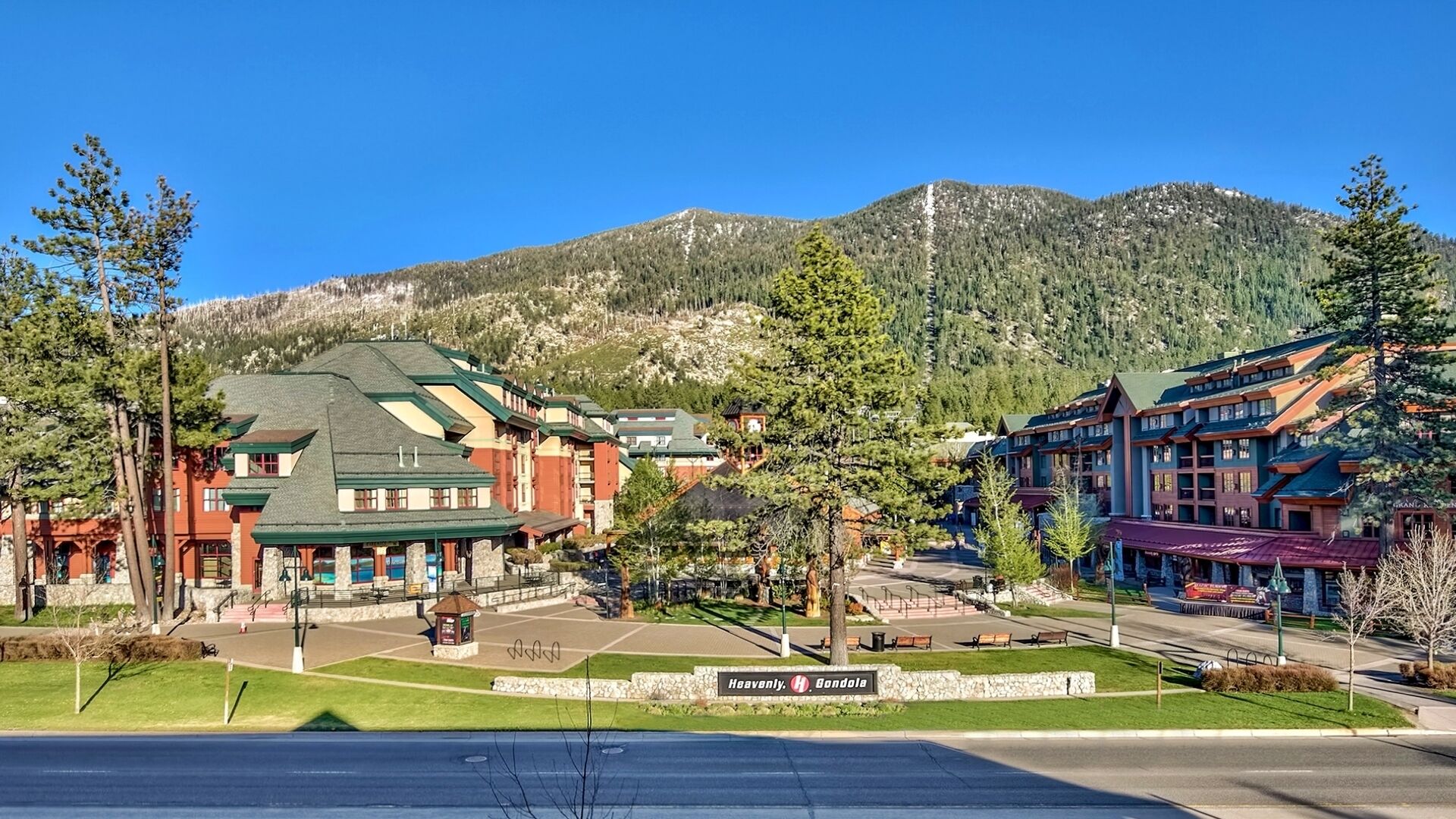 A hotel with a green roof, a sign reading "Heavenly Gondola," and a mountainous backdrop.