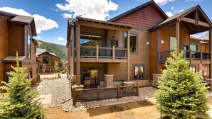 A modern multi-story lodge with a covered outdoor area, stone pathway, and surrounding trees. - River Run Townhome RR84 - RVJR by RedAwning (Keystone)
