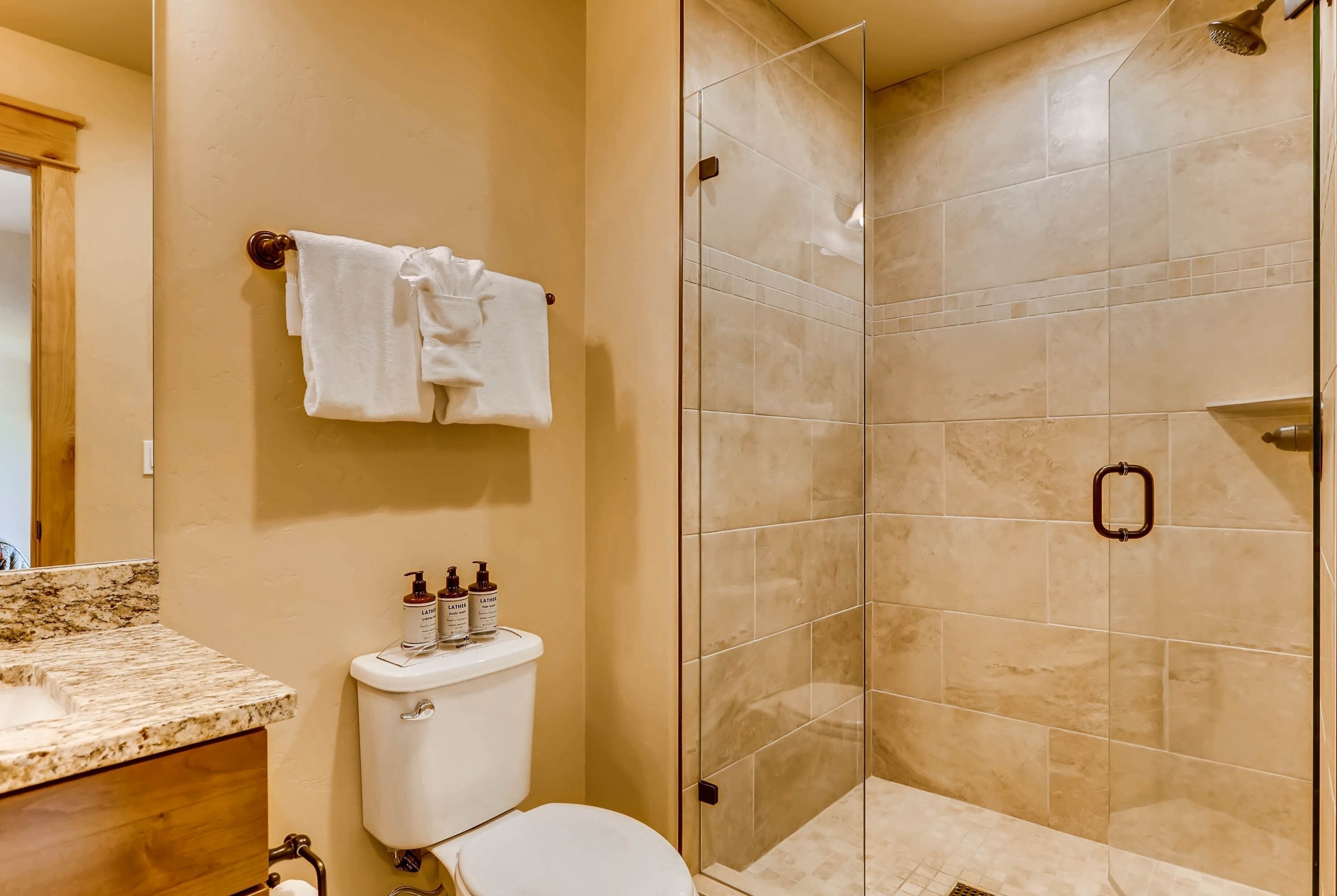 A bathroom with a toilet, sink, and glass shower enclosure.