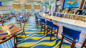 A hotel lobby with a bar area, seating arrangements, and a patterned carpet.