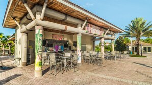 An outdoor seating area with tables and chairs, a covered patio, and a sign for "The Oasis Tiki Bar".