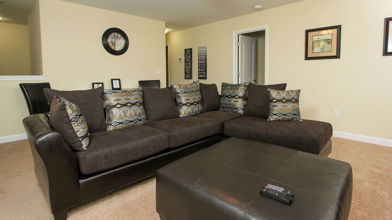 A living room with a sectional sofa, a coffee table, and a door leading to another room.