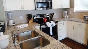 A modern kitchen with white cabinets, stainless steel appliances, a granite countertop, and a double sink. - Fd57055 - Lucaya Village - 4 Bed 3 Baths Townhouse (Kissimmee)