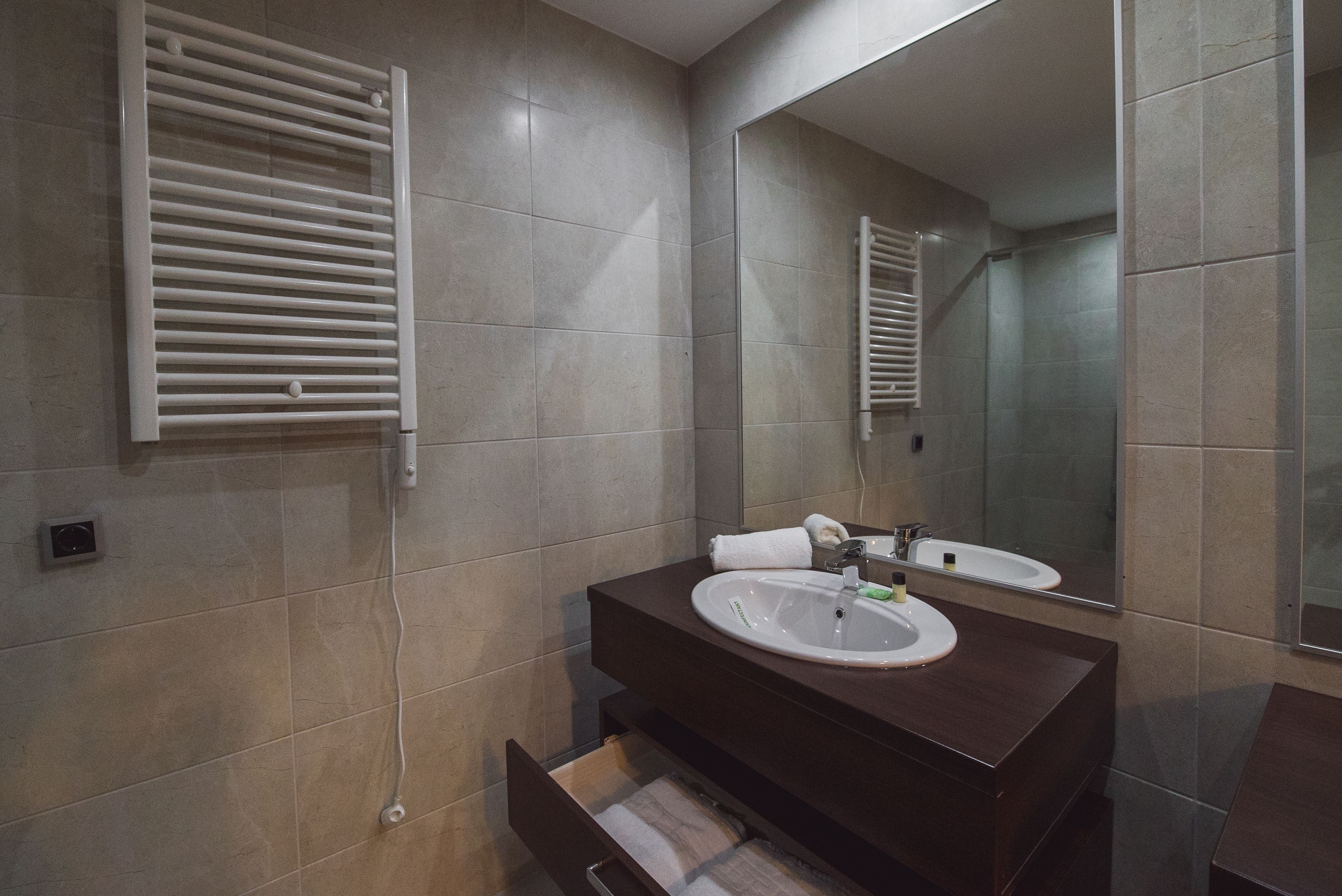 A modern bathroom with a dark wooden vanity, a white sink, and a large mirror.