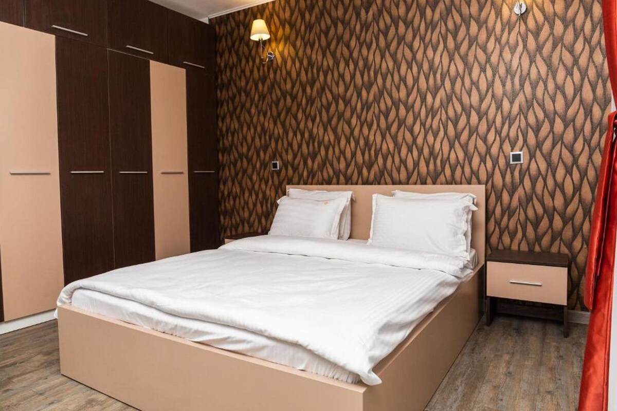 A bedroom with a bed, nightstand, and wardrobe.