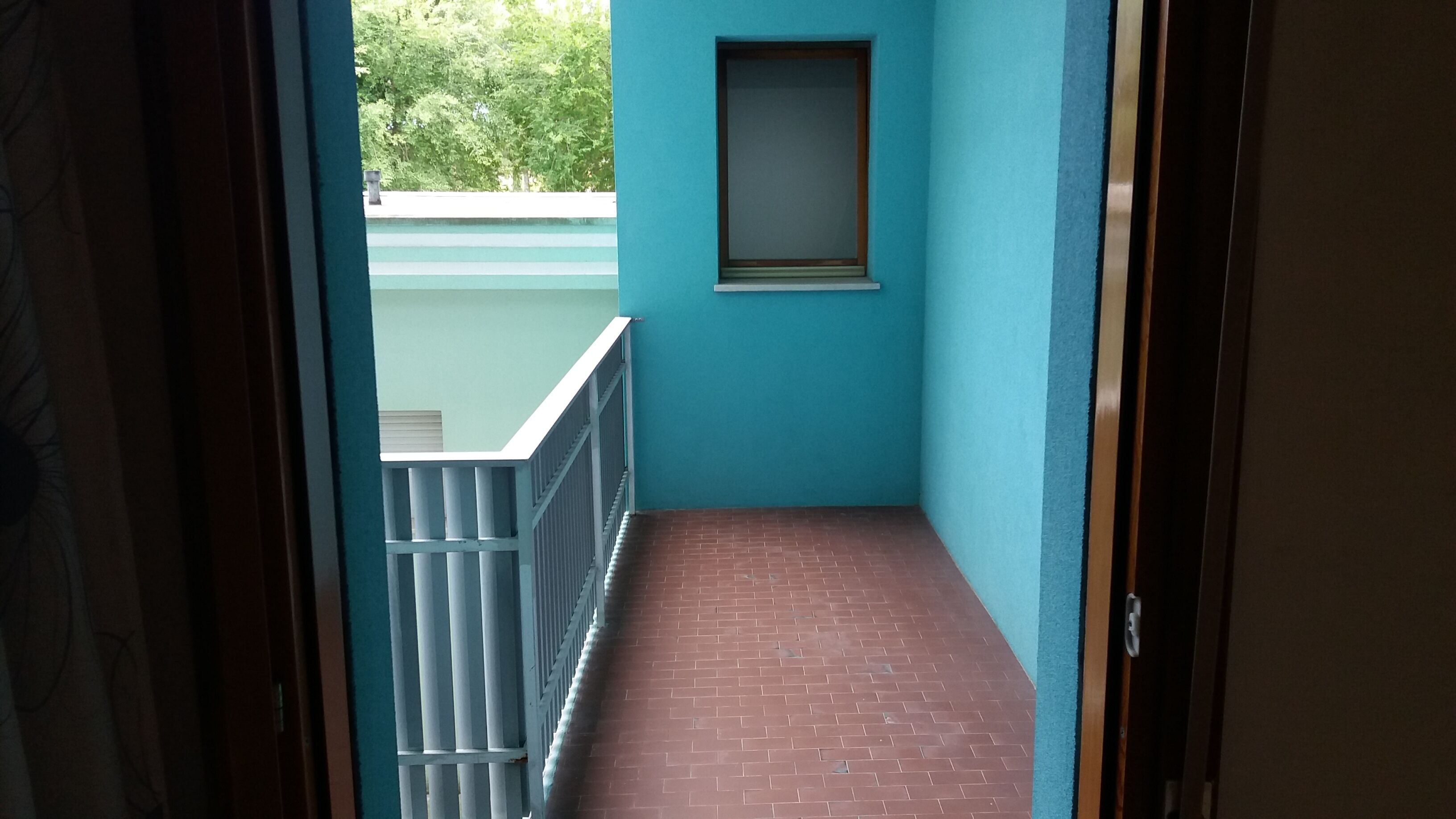 Een smalle gang met een blauwe muur en een raam.