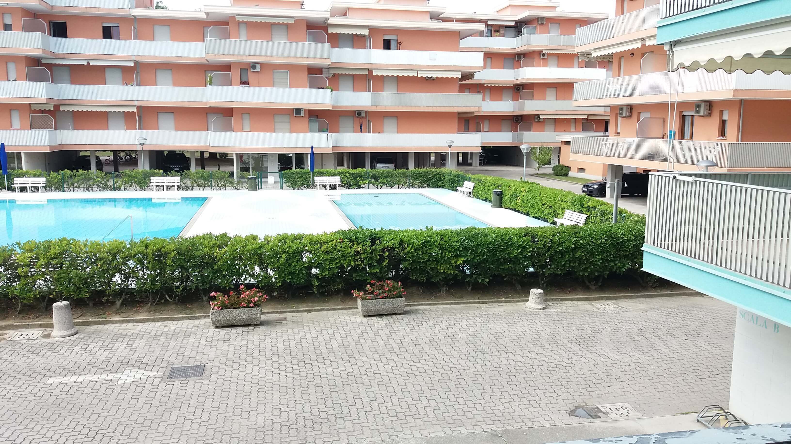 Ein Innenhof mit einem Schwimmbad, umgeben von Mehrfamilienhäusern mit Balkonen.